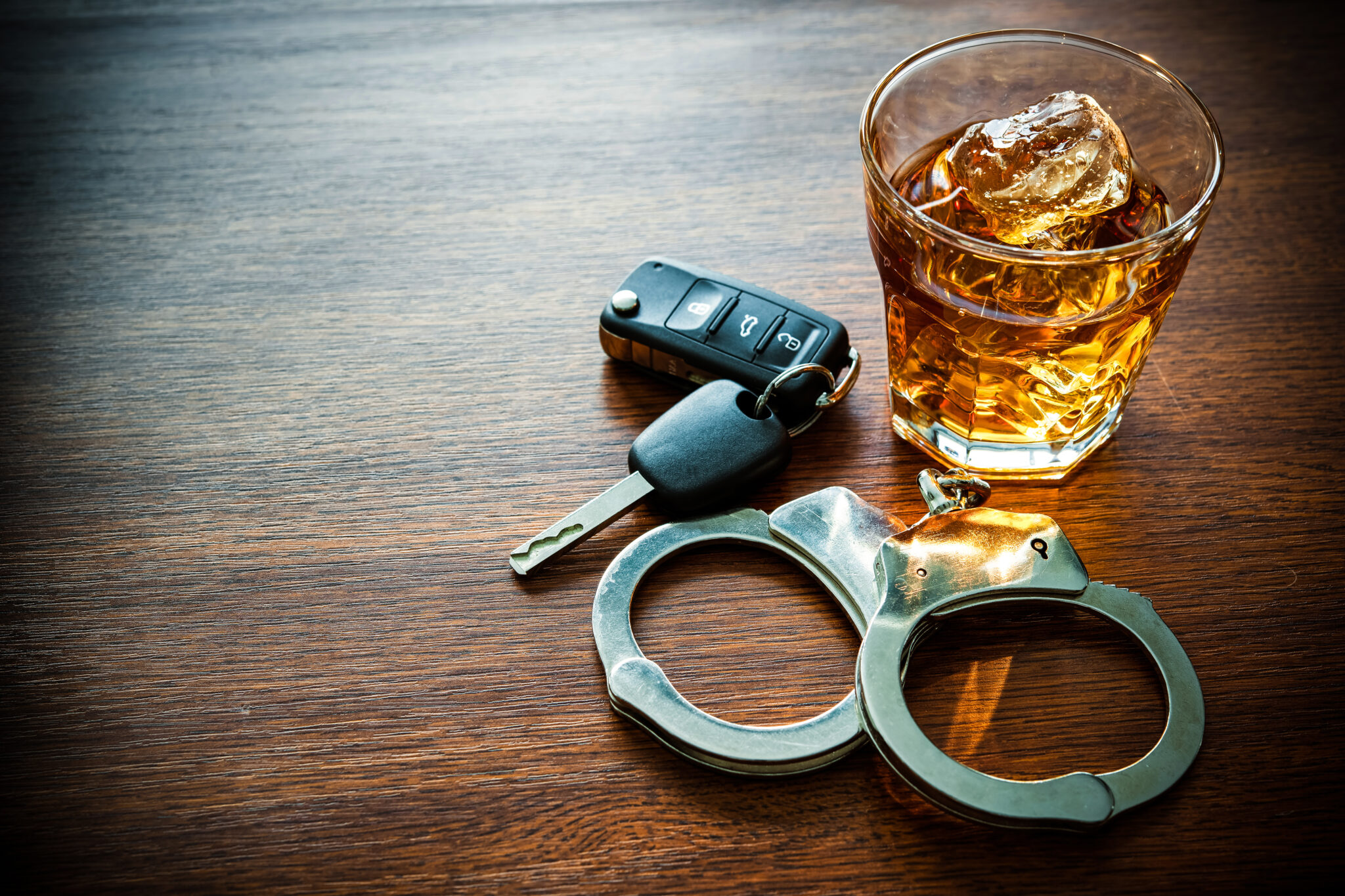 Glass of whiskey with car keys and handcuffs