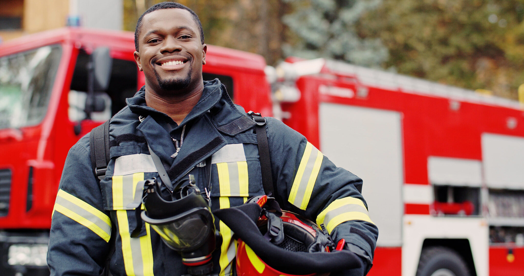 Smiling firefighter in front of engine.