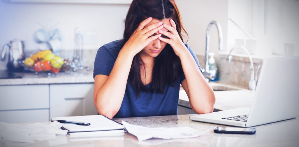Stressed woman looking down at bills.