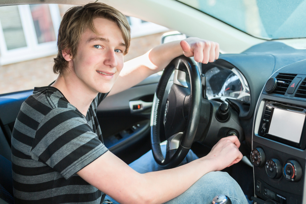 Teenage boy behind wheel of his car